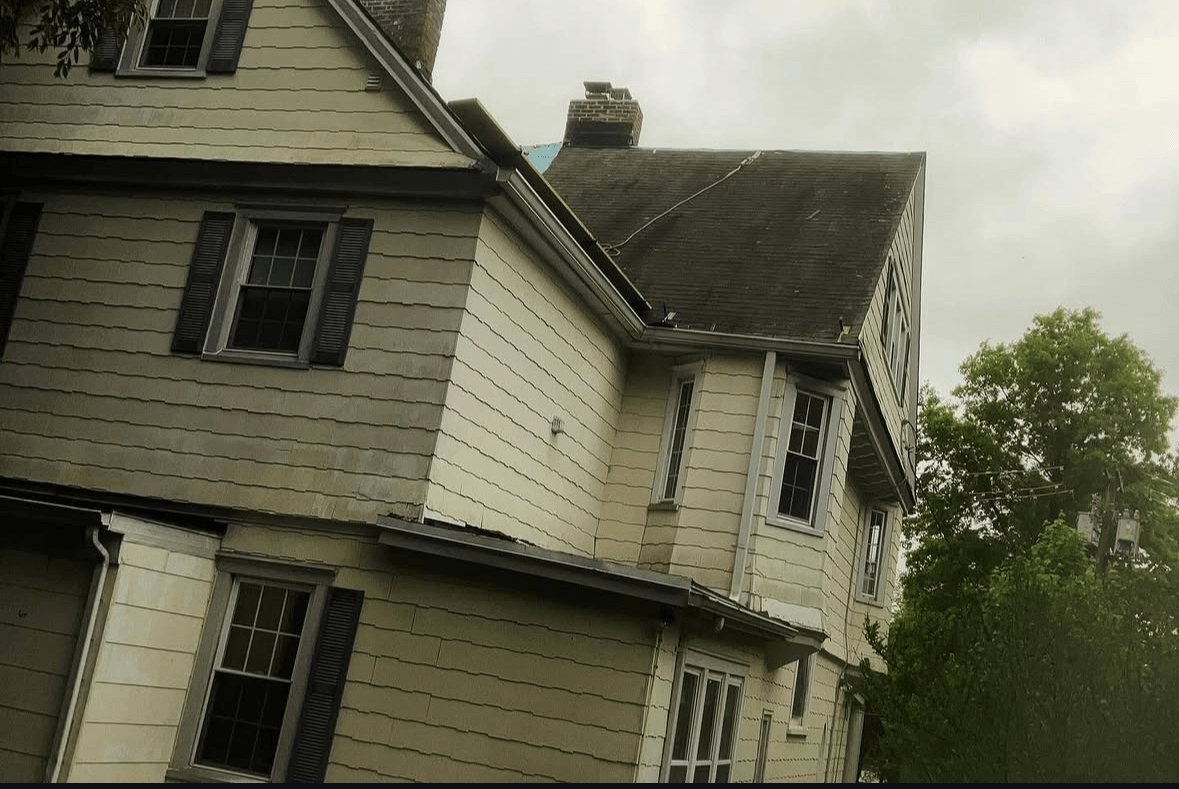 Close-up of the original weathered siding, trim, and roofline before renovation